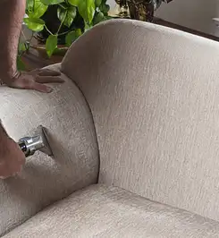 Professional upholstery cleaner deep-cleaning a fabric sofa with a handheld extraction tool and hose Lakewood, CO.